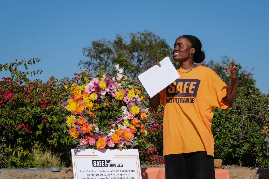 Justice Action Center Communications Coordinator Joan Agoh speaks at a #SafeNotStranded rally at San Diego’s Balboa Park