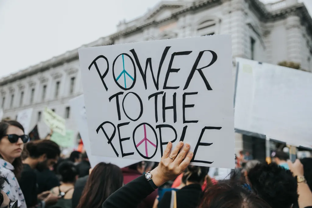 Photo of a demonstrator holding a sign that reads "Power to the People"