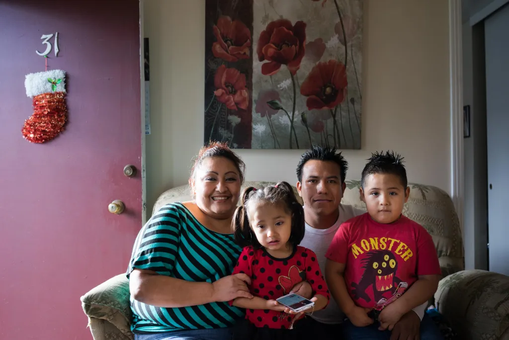 Parents and two children sitting on a couch in their living room, evoking hope and togetherness in a season of financial need and community support.