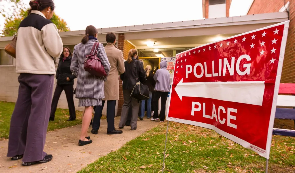 Voting polling place sign and people lined up on presidential election day.