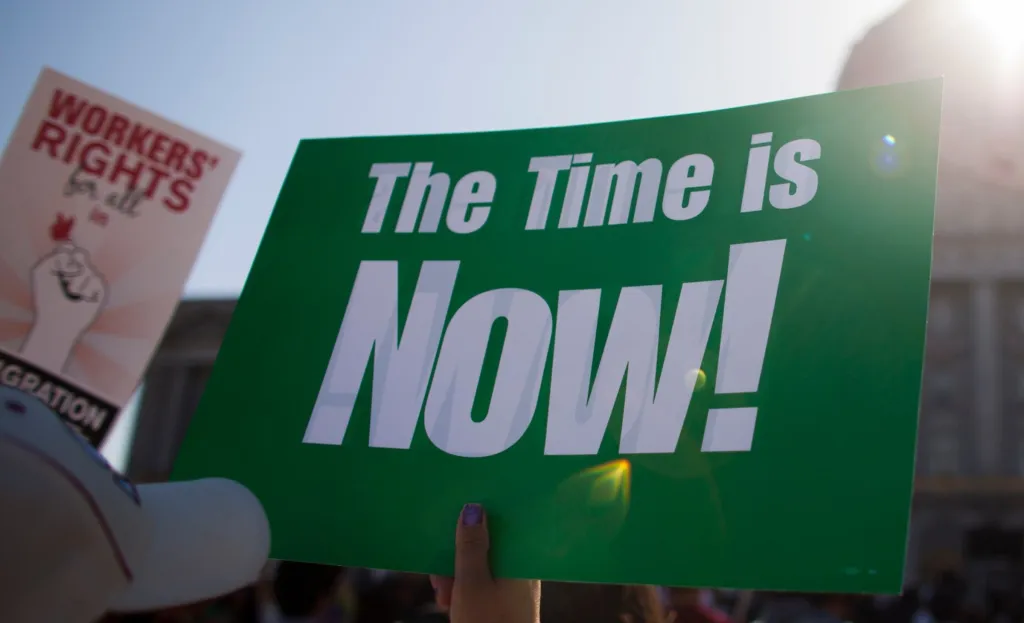 "Time is Now" sign held at protest