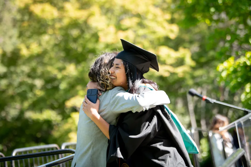 Photo of an undocumented college grad hugging someone on stage during graduation