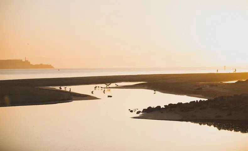 Sunset at the beach with people playing