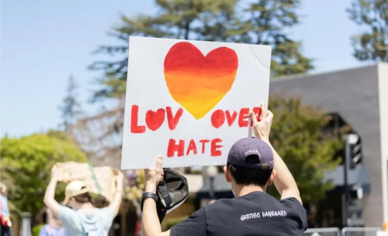 Photo of a demonstrator holding a sign that reads "Love Over Hate"