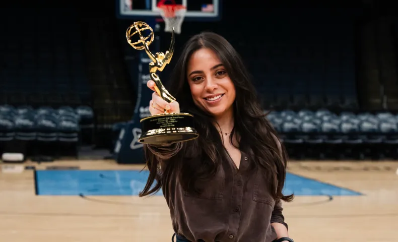 Woman holding Emmy award on basketball court