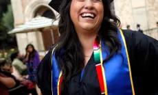 Student with cap and gown smiles at graduation