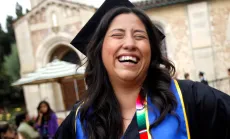Student with cap and gown smiles at graduation