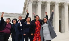 Five students stand in front of SCOTUS with their fist in the air