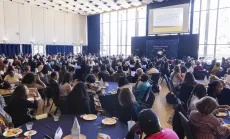 Large audience seated at round tables in a conference hall, listening to speakers on stage at the Berkeley Public Policy Annual Conference and Alumni Gathering 2023.