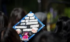 Closeup of a graduation cap that reads "Paving the way for my familia and comunidad. Educated mujer first gen"