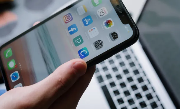 Someone holding a cell phone with social media apps visible on its screen