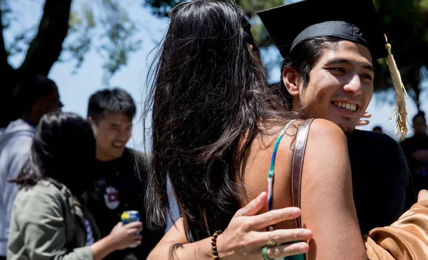 Jirayut “New” Latthivongskorn hugs a high school friend while wearing his mortarboard during his graduation party at Marina Park in San Leandro to celebrate his achievement at UCSF’s School of Medicine.