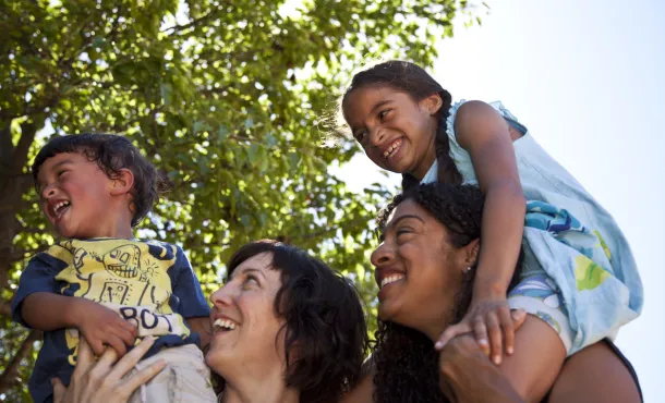 Lesbian moms smile with their son and daughter