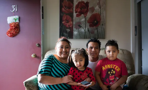 Parents and two children sitting on a couch in their living room, evoking hope and togetherness in a season of financial need and community support.