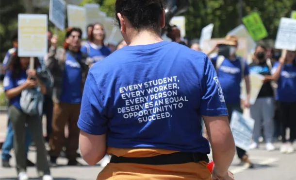 Photo of a demonstrator whose shirt reads "Every Student, Every Worker, Every Person Deserves an Equal Opportunity to Succeed"