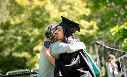 Photo of an undocumented college grad hugging someone on stage during graduation