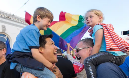 Boy and girl on the shoulders of their dads