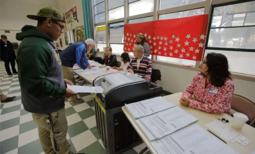 A young person dropping his ballot into a ballot box