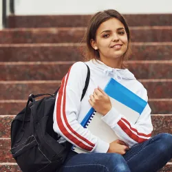 Young student sitting on stairs with books