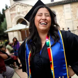 Student with cap and gown smiles at graduation