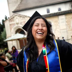 Student with cap and gown smiles at graduation