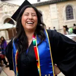 Woman in cap and gown smiling at graduation