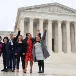 Five students in front of SCOTUS with fist in the air