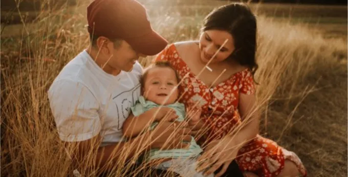 A family photographed sitting in a field.