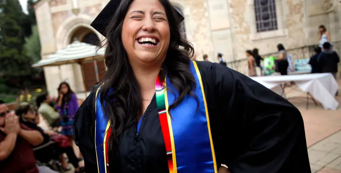 Woman in cap and gown smiling at graduation