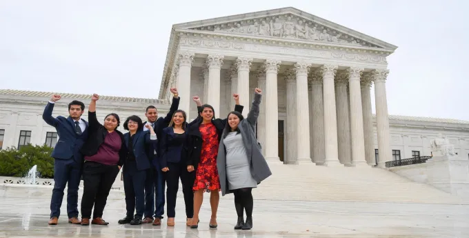Five students in front of SCOTUS with fist in the air